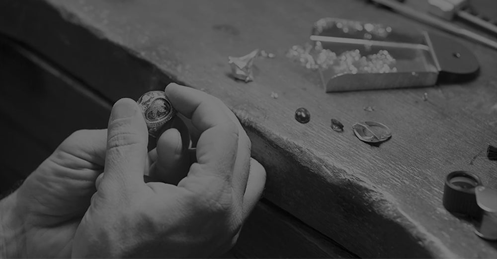 A person holding a ring with a jewelry-making setup and diamonds