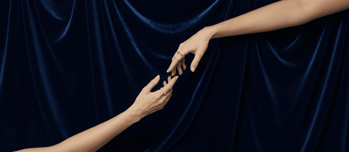 Two hands reaching towards each other against a dark blue velvet curtain