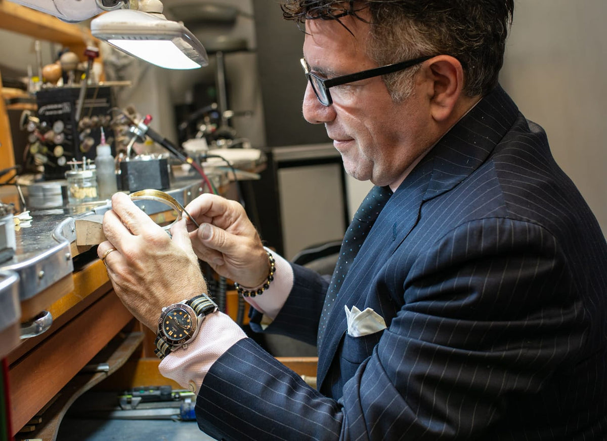 A man in a suit working on jewelry in a workshop